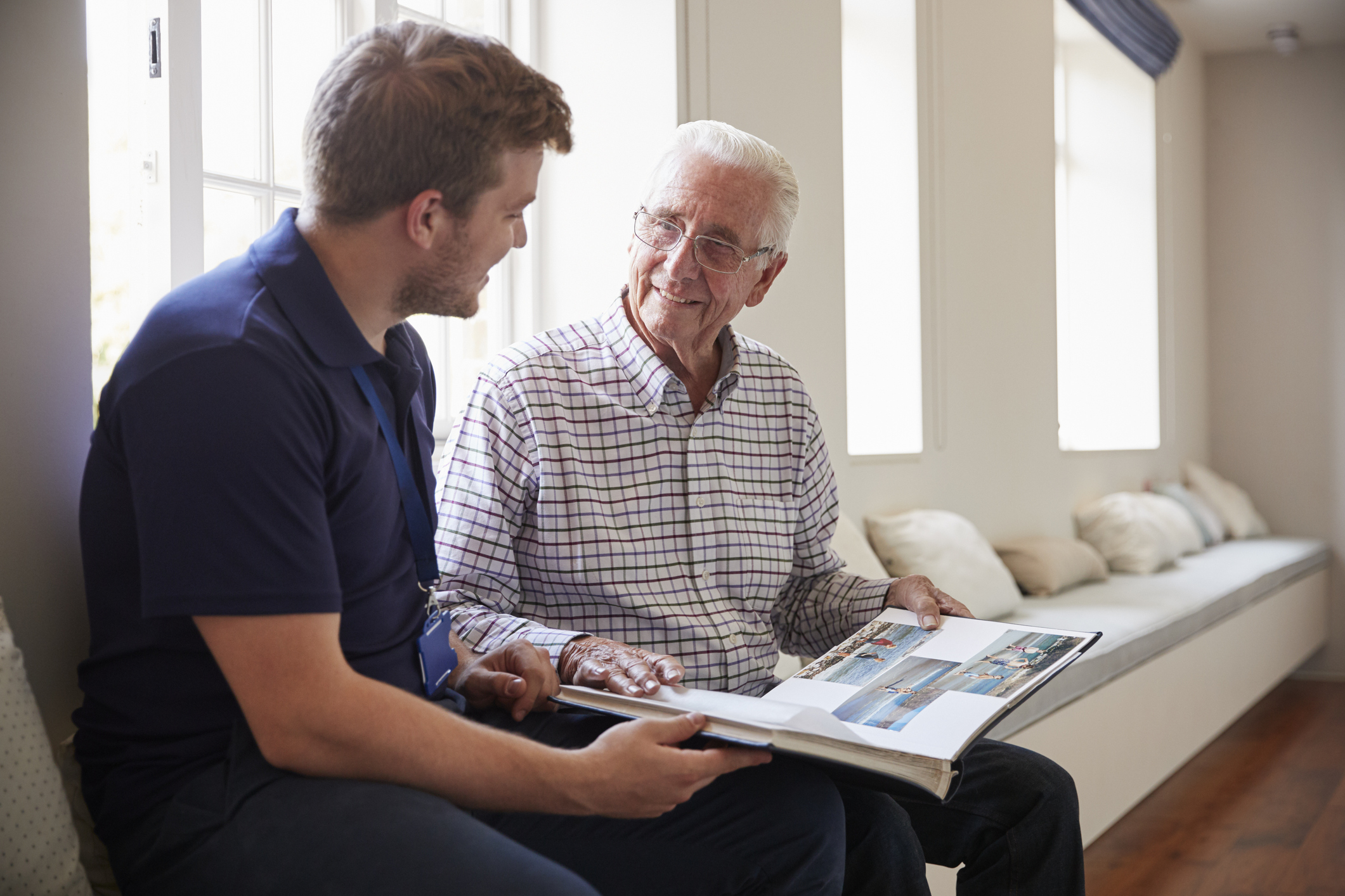 Senior man sitting looking at photo album with male nurse men_looking_at_photo_book