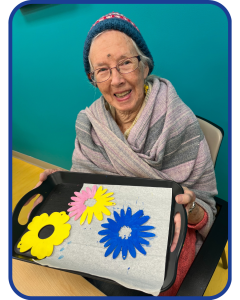 Our members enjoy daily crafting activities. Here a member displays their painted flower craft.