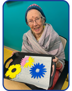 Our members enjoy daily crafting activities. Here a member displays their painted flower craft.