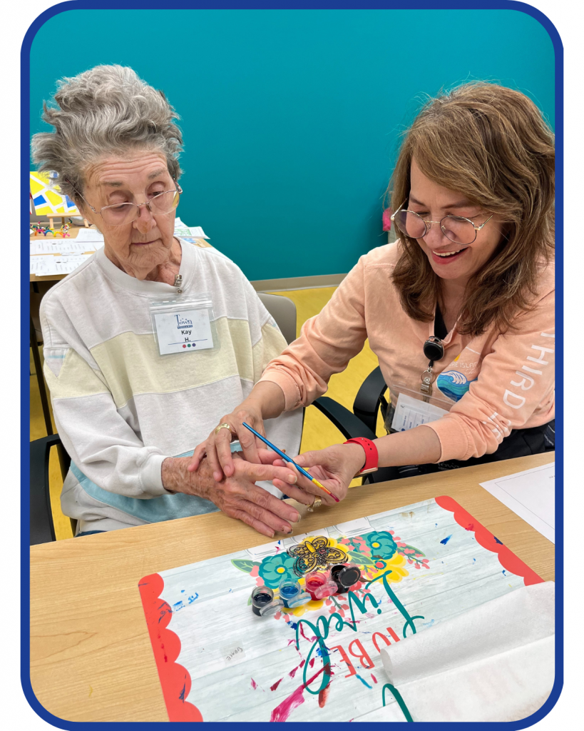 A caregiver working hand-over-hand with a senior to complete a craft project