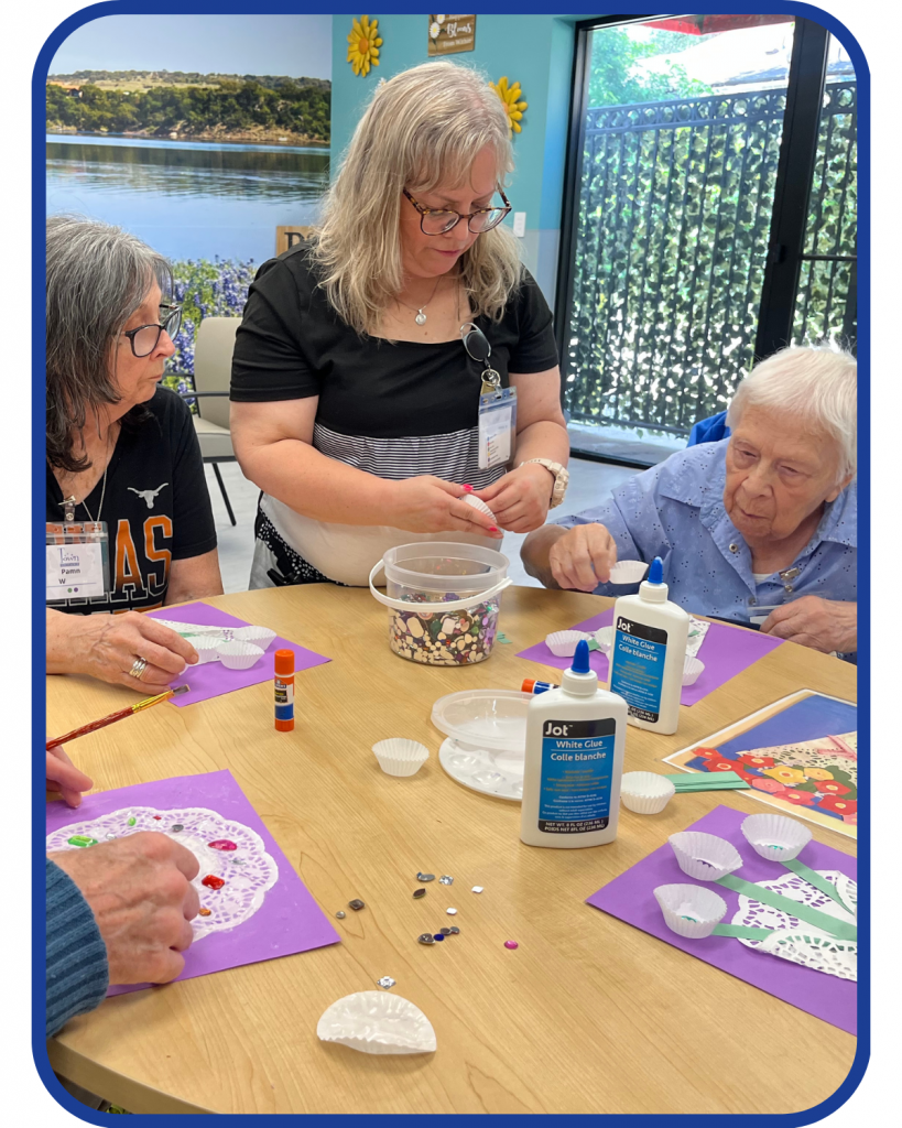 a group of older women at a circular table working on crafts together.